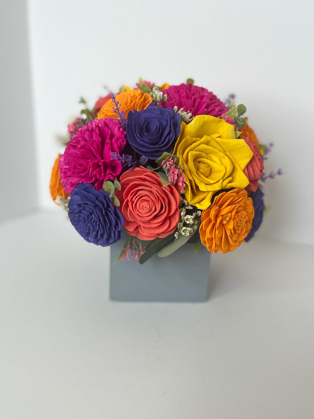 Bright colored summer bouquet with purple, yellow, orange & pink wooden flowers placed in grey box.