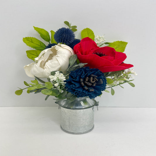 Red, white & navy flower bouquet with greenery placed in silver mini milk can. 