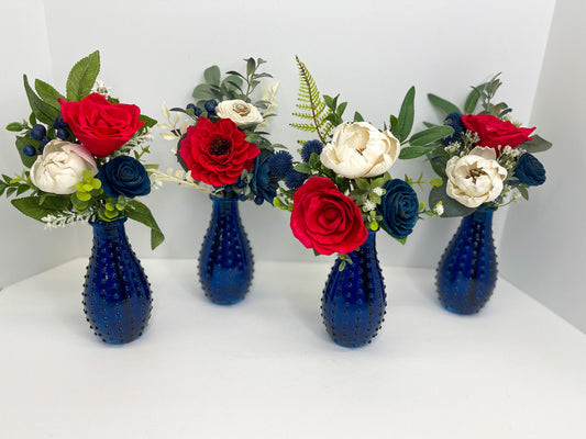 Red, blue, and white USA wooden flower bouquet with greenery placed in navy bud vase.
