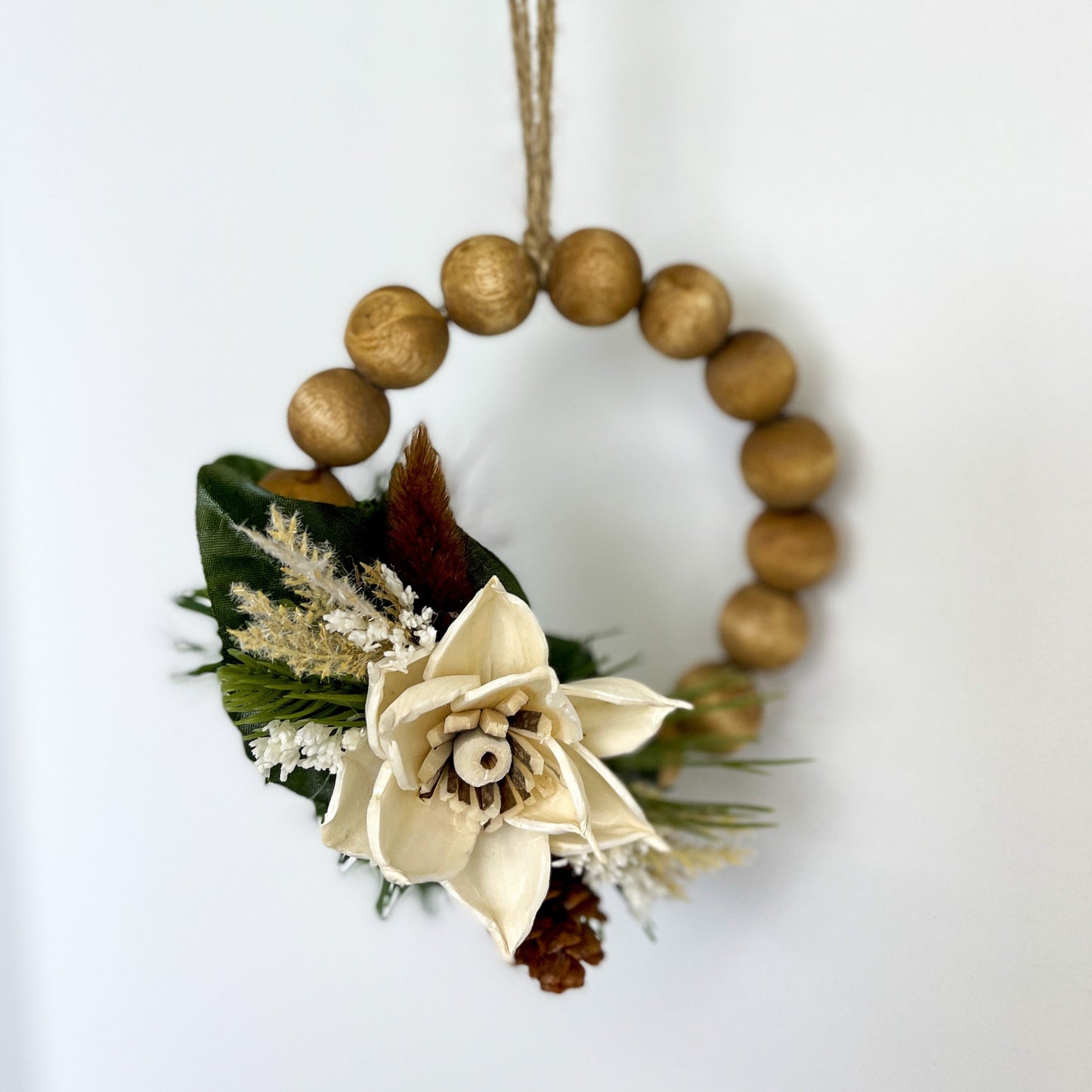 Gold beaded wreath ornament with green decor and ivory, wooden, handcrafted floral. 
