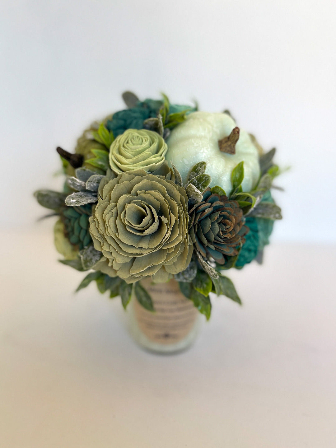 Multicolored green flowers with white pumpkin bouquet placed on top of "Mint Mojito" candle. 