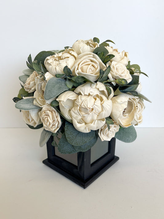 Ivory flowers and greenery bouquet within square, black, rotating picture frame. 