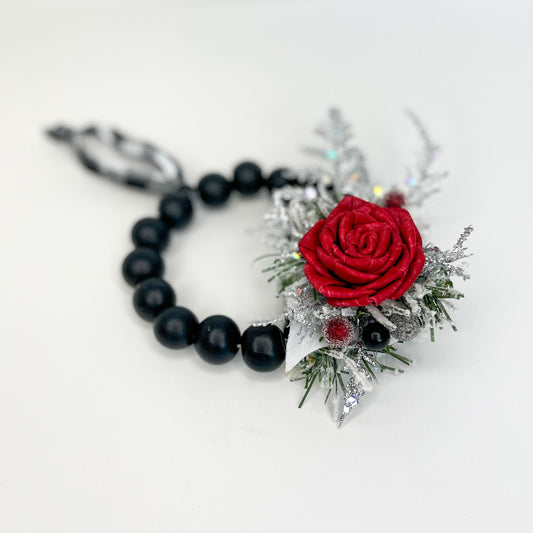 Black beaded wreath ornament with silver and green tinsel and red, handcrafted, wooden flower. 